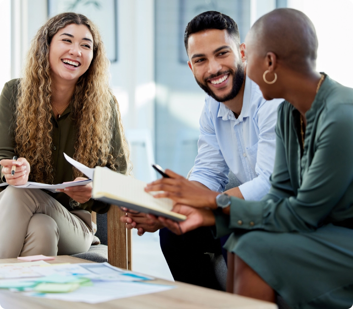 Three people smiling during a meeting.
