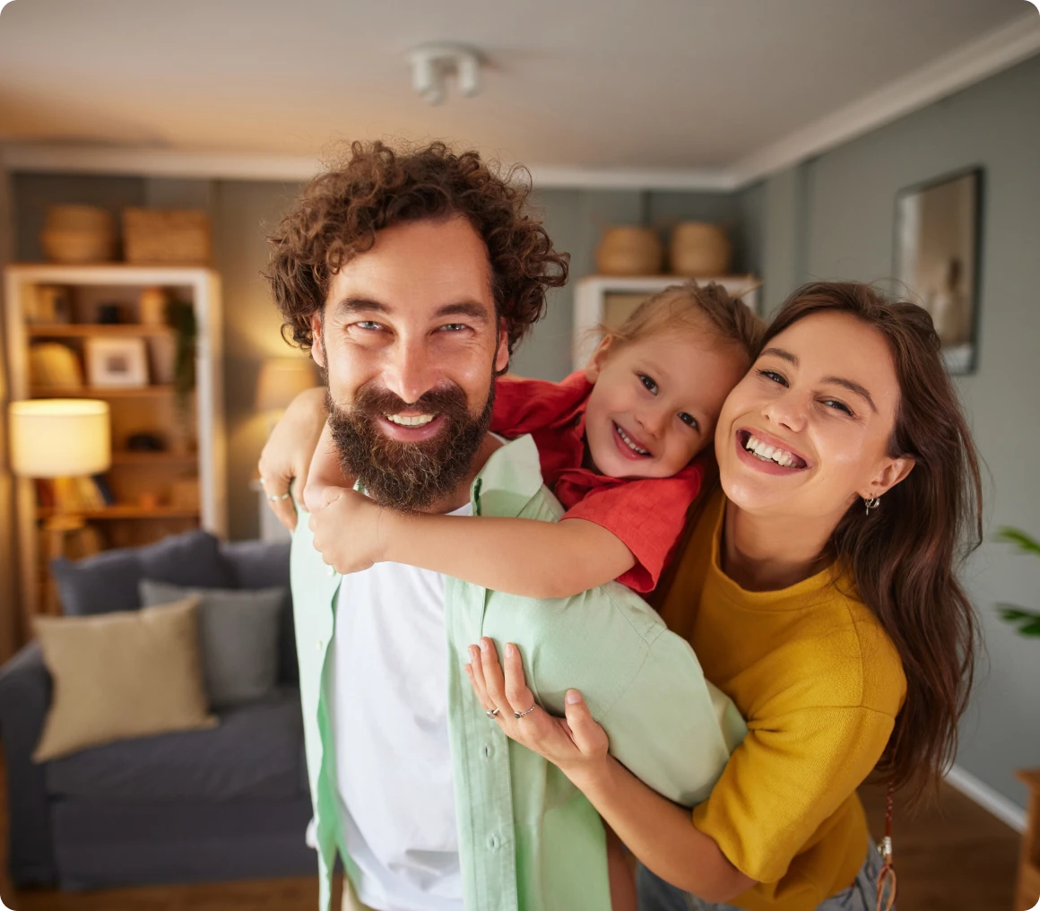 Smiling family posing in cozy living room.