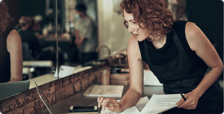 Woman working with documents and laptop.