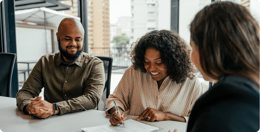 People signing documents at a meeting table.