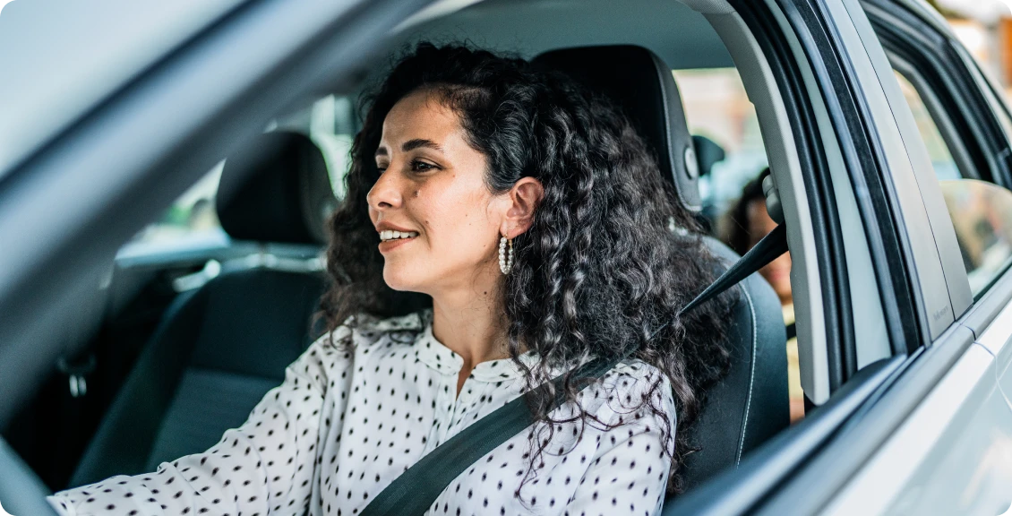 Woman driving car, smiling and confident.